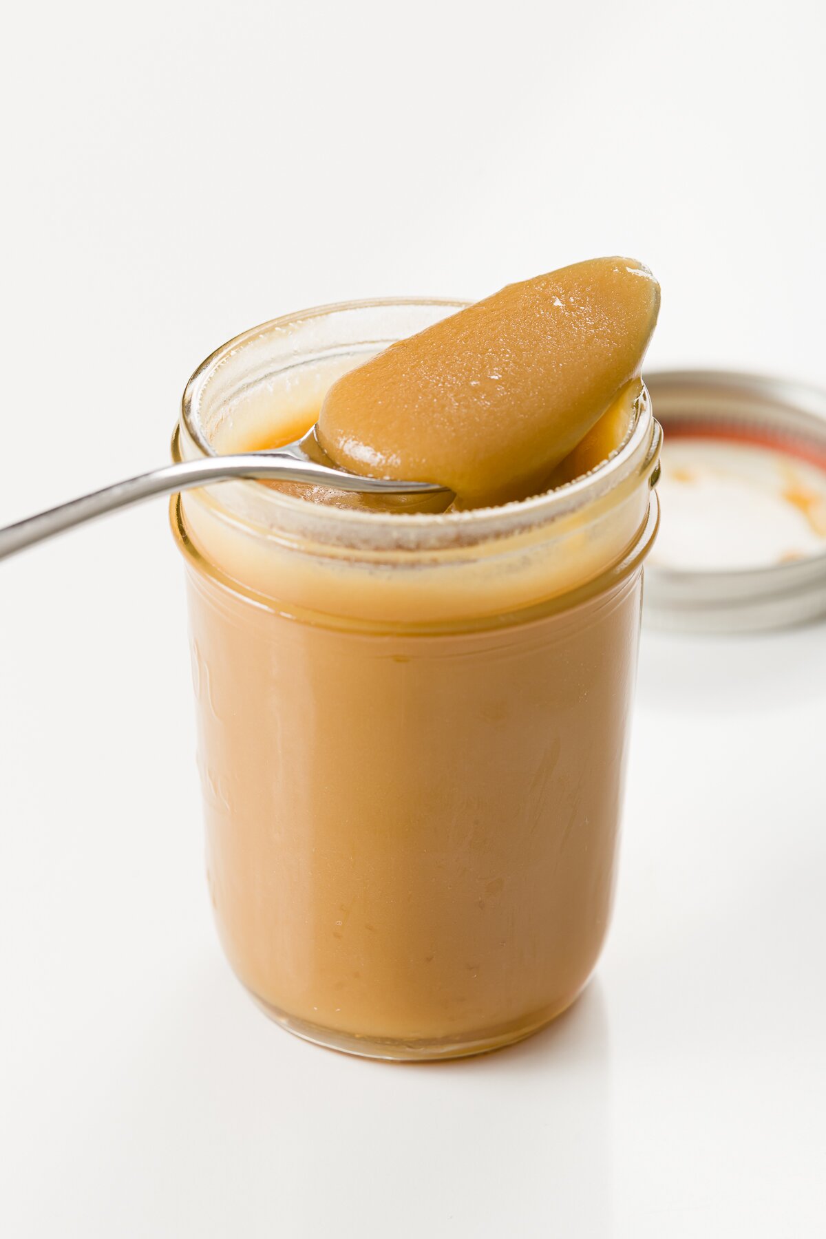 Jar of whiskey sauce with a spoon resting on top