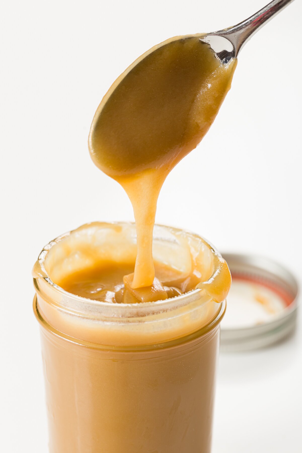 Whiskey sauce being poured into a jar from a spoon