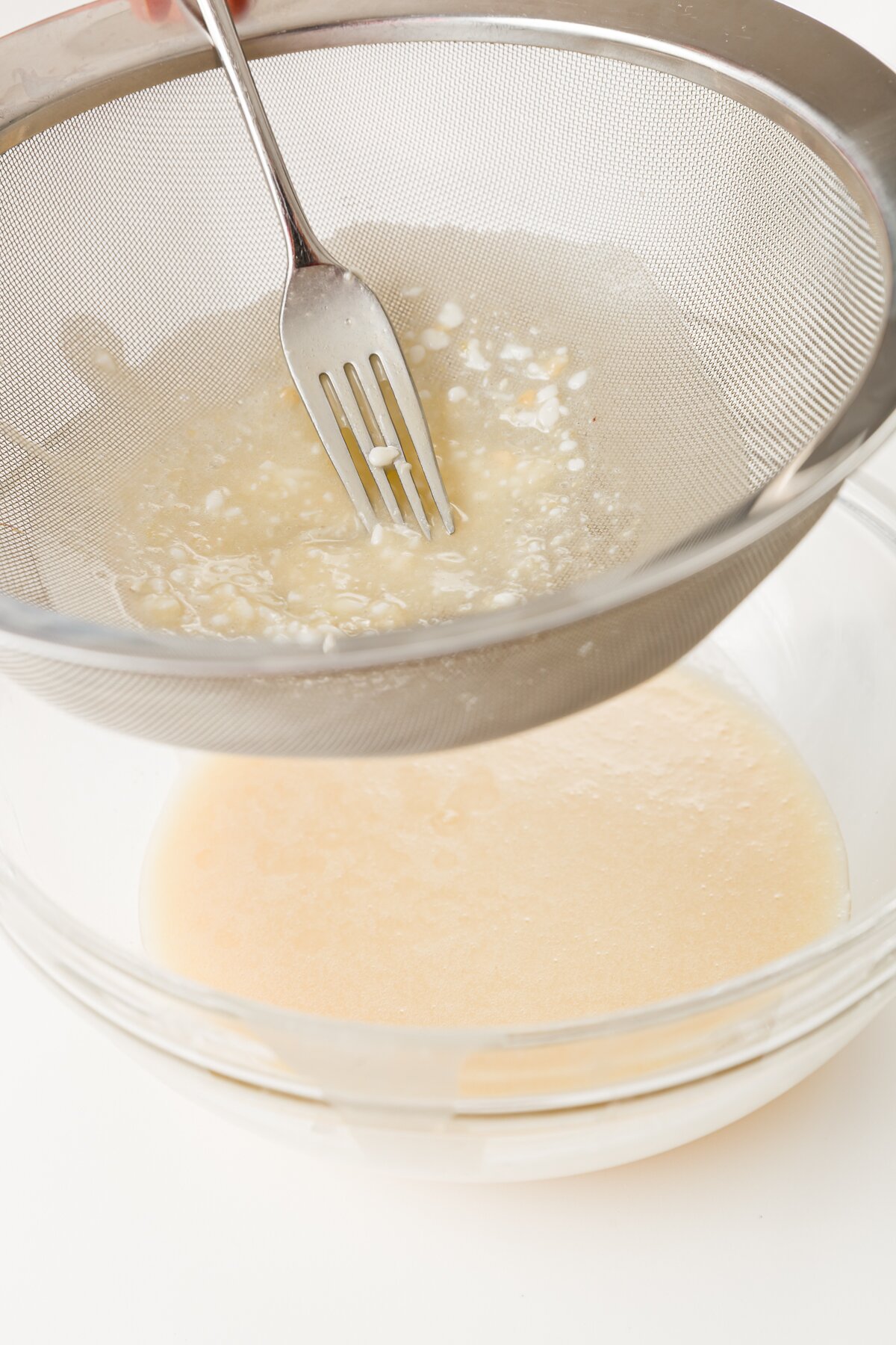 Pushing batter through a sieve with a fork