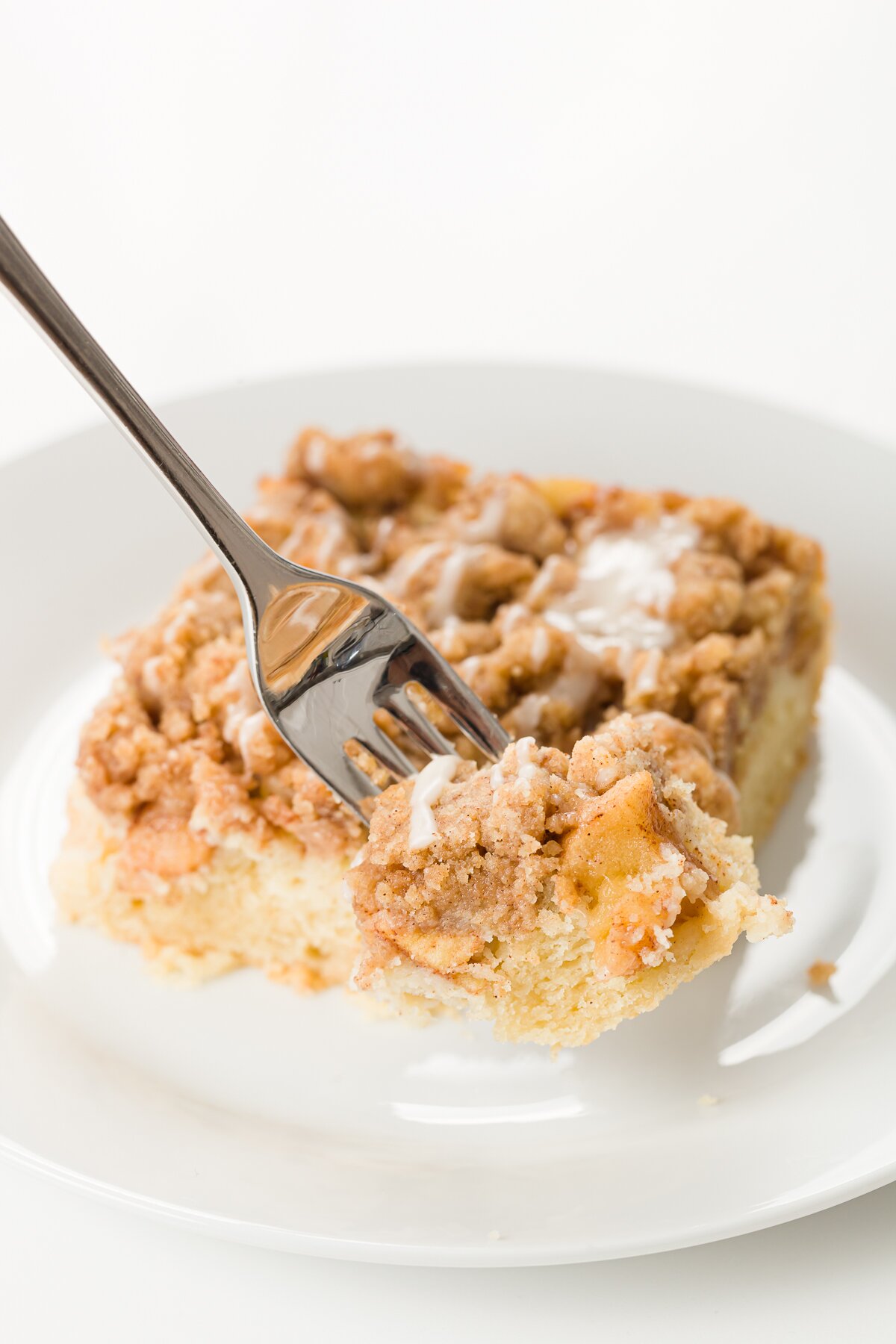 Fork lifting off a bite of apple crumb cake