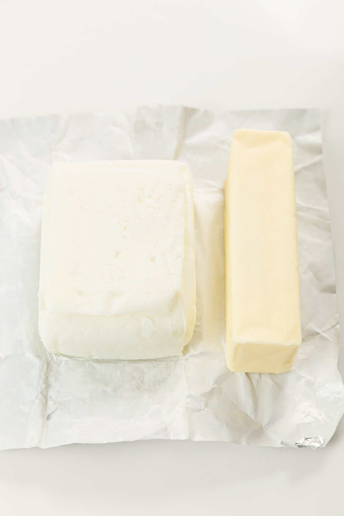 Block of goat butter next to a stick of cow's butter