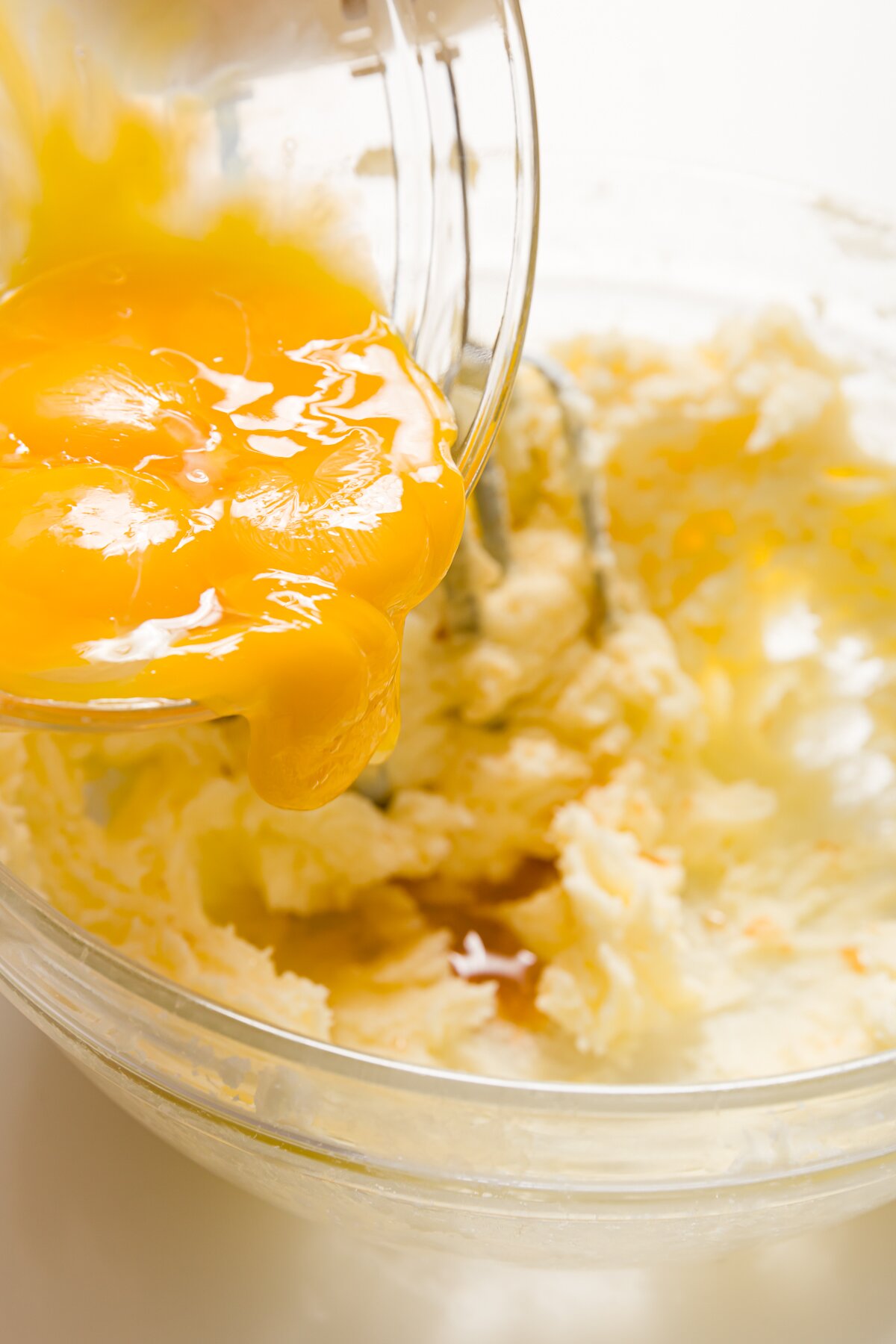 Adding egg yolks to batter in a glass bowl
