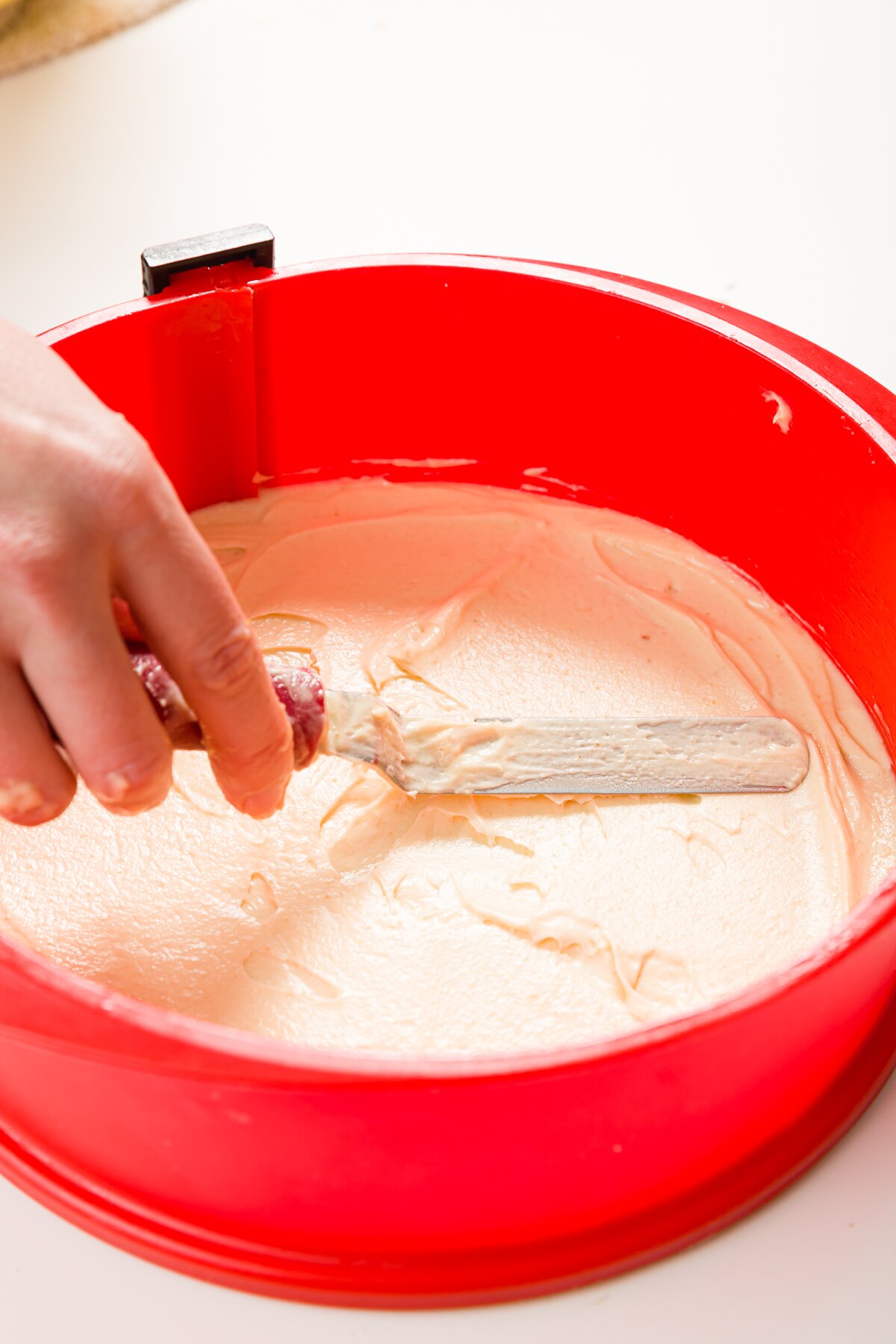 Spreading a thin layer of batter in a red springform pan