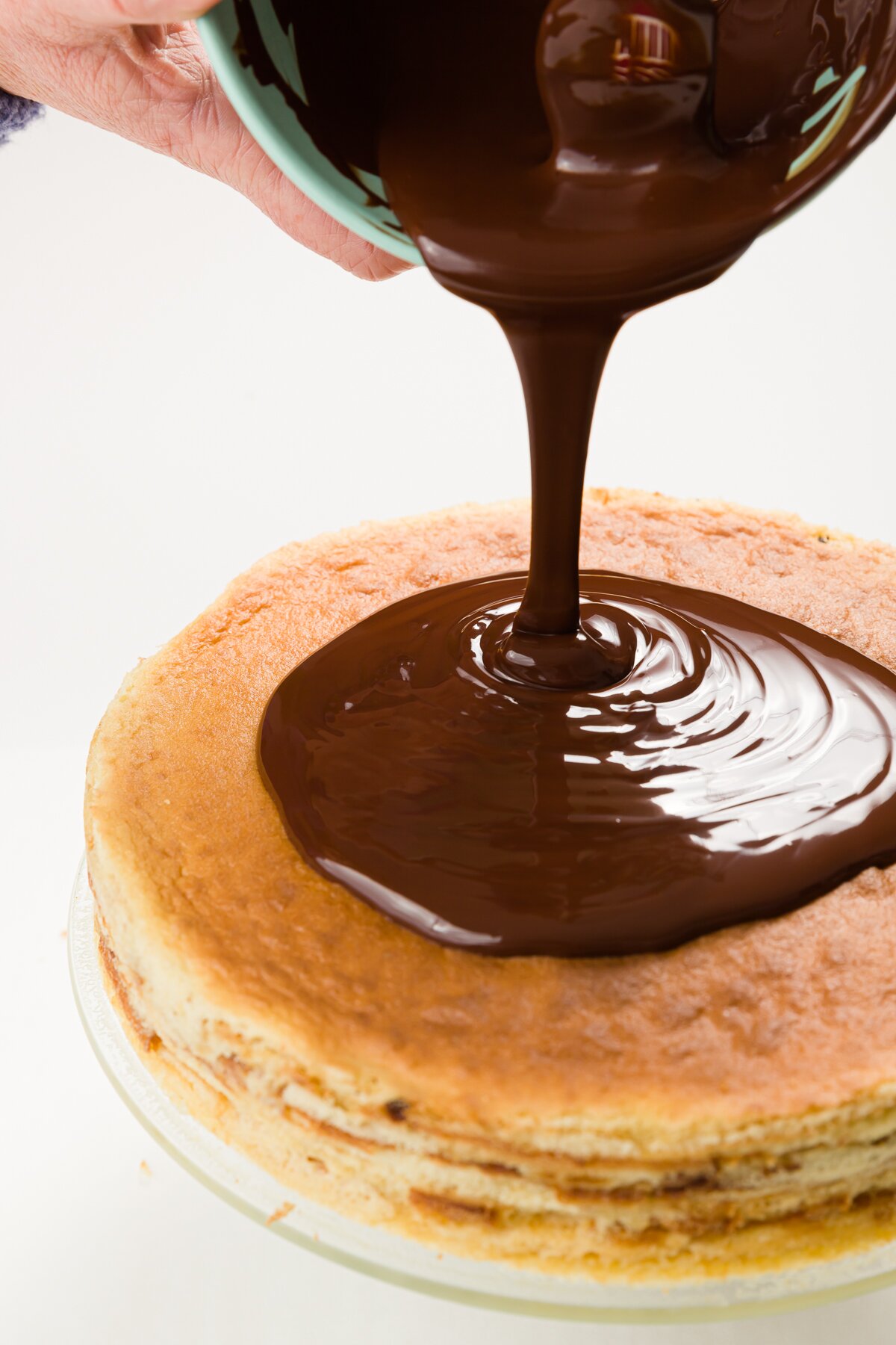 Pouring chocolate over top of a cake