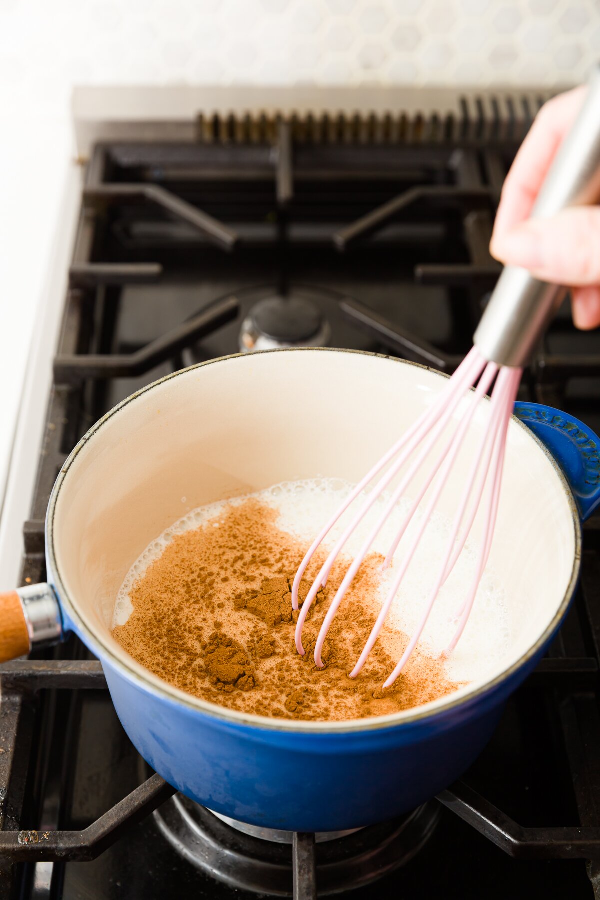 Whisking milk and cinnamon in a blue saucepan