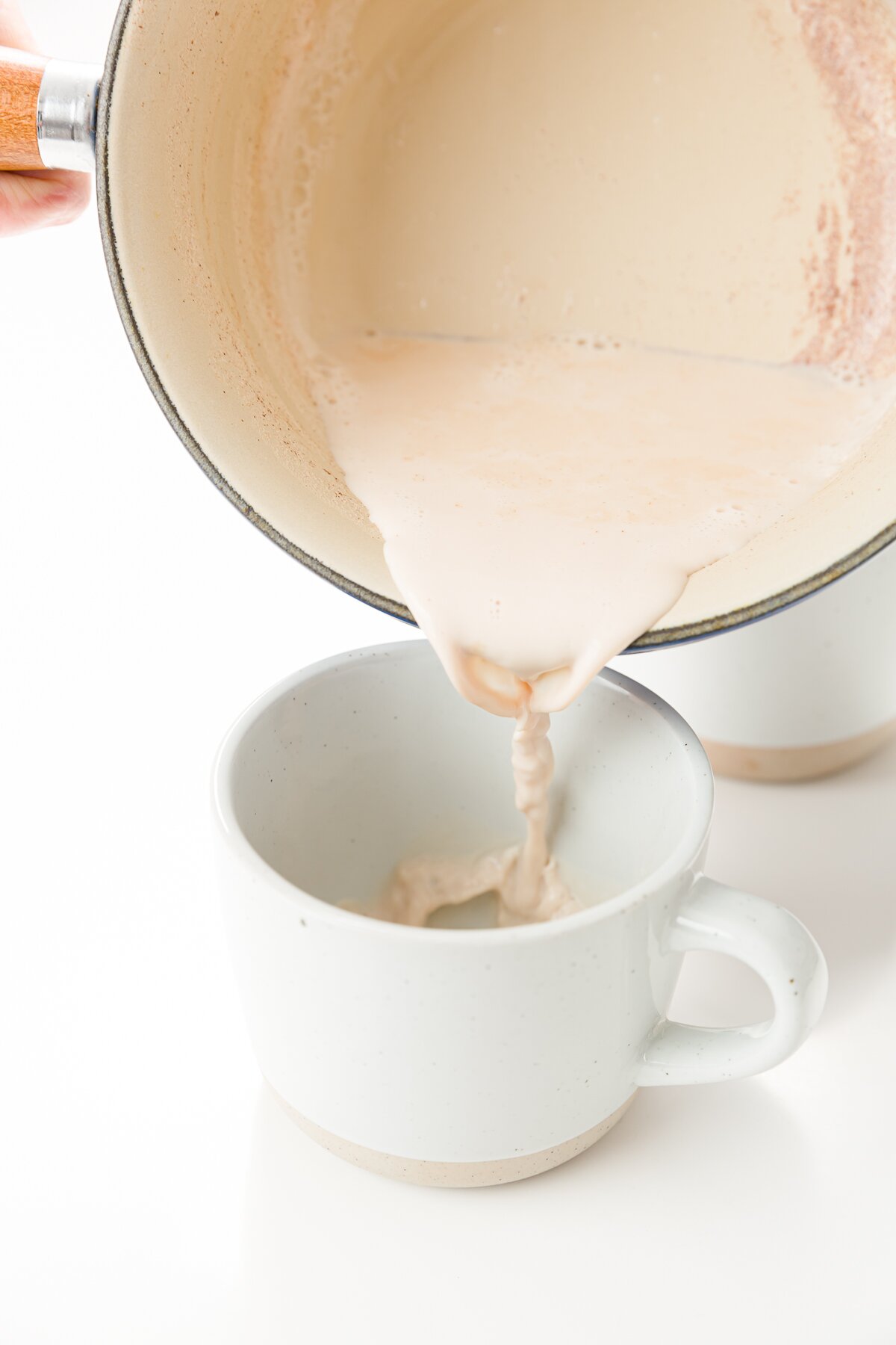 Pouring cinnamon milk from a saucepan into a mug