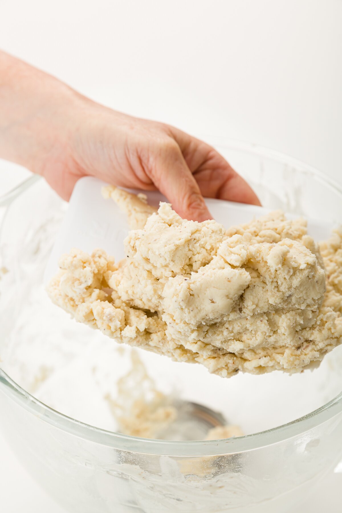 Removing shortbread dough from the mixing bowl on a bench scraper