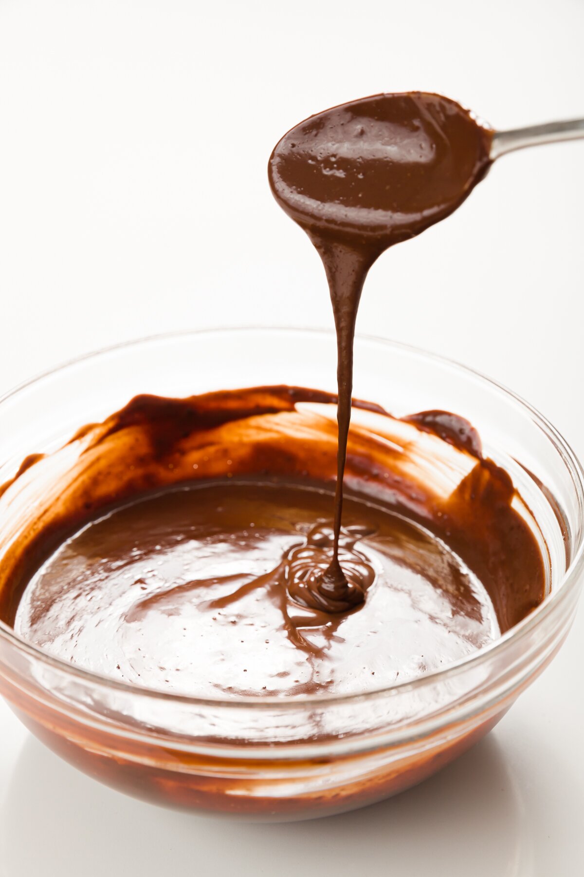 Mexican chocolate sauce dripping off a spoon into a glass bowl