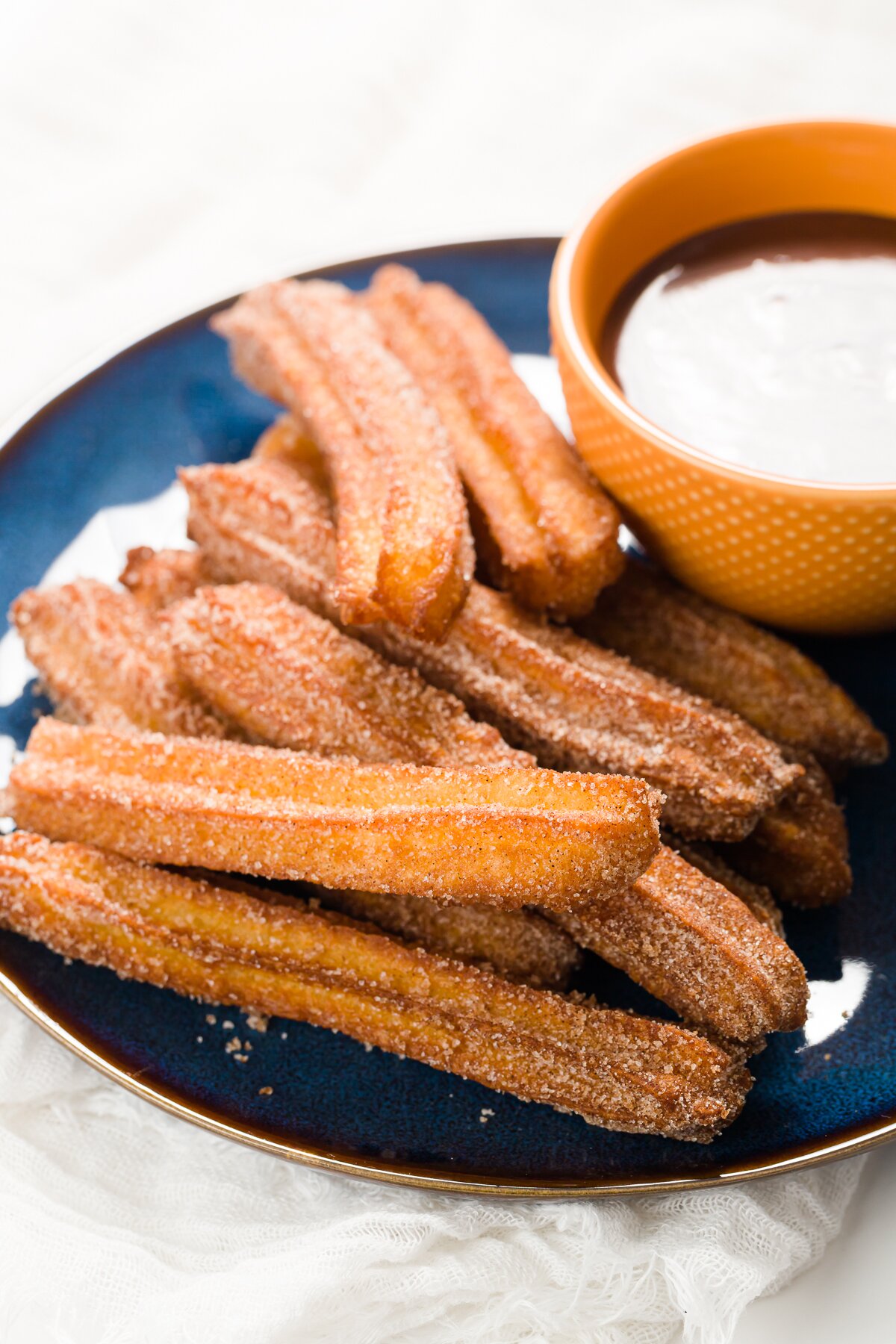 Plate of churros with a bowl of chocolate sauce on it