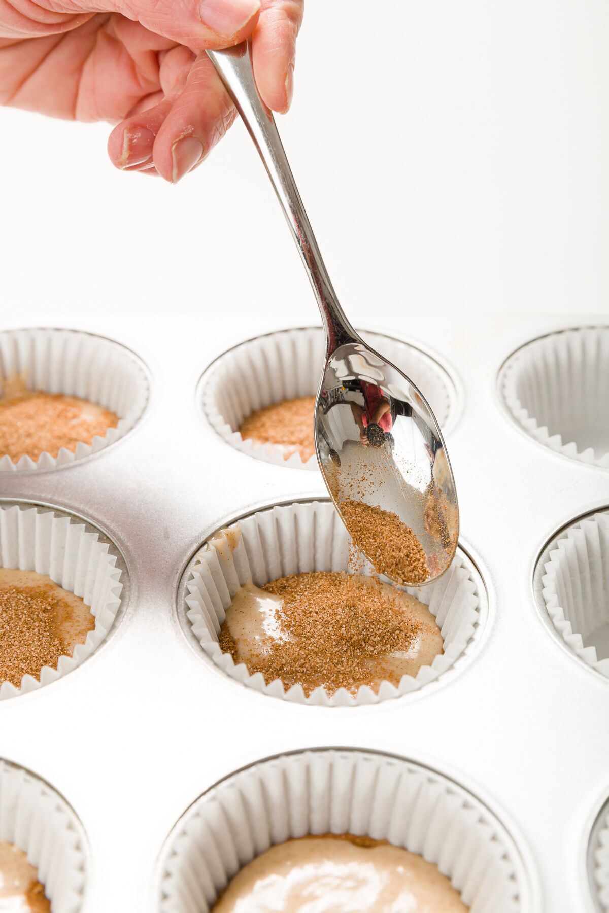 Adding cinnamon sugar to cupcake liner with a teaspoon