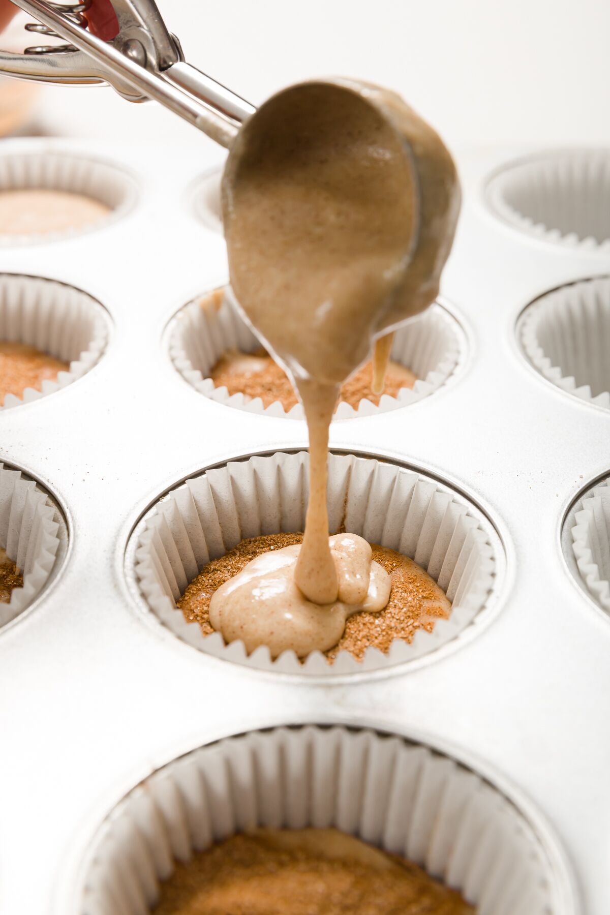 Using a scoop to add batter to cupcake liner