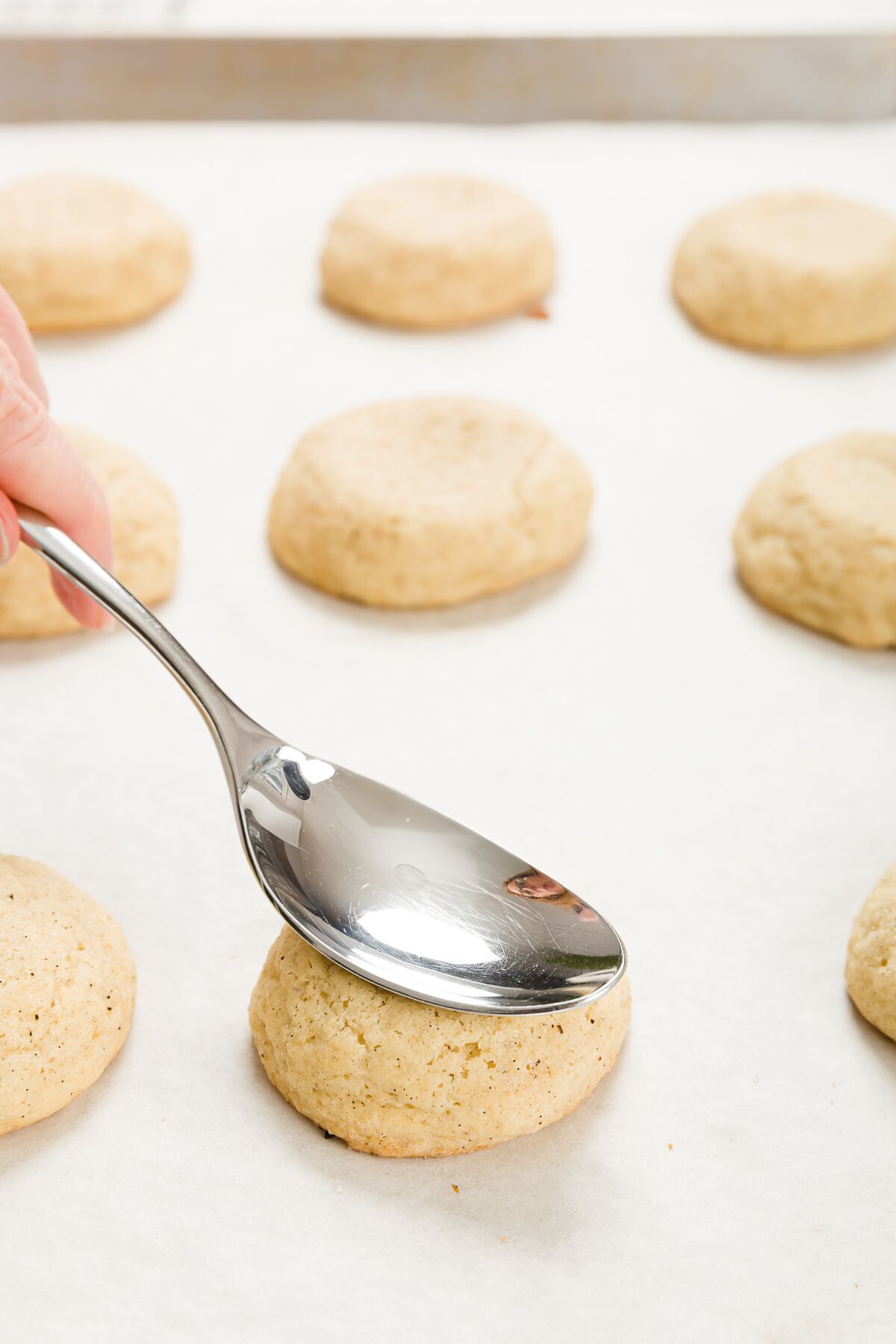 Pressing the center of a cookie down with a spoon