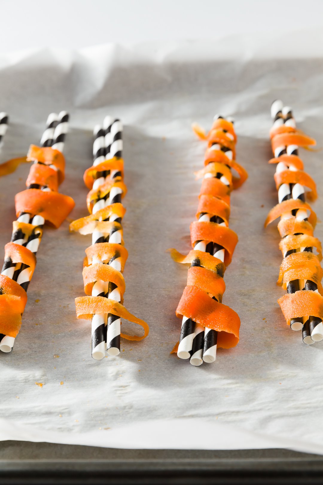 Carrot ribbons wrapped around paper straws to create candied carrot curls.