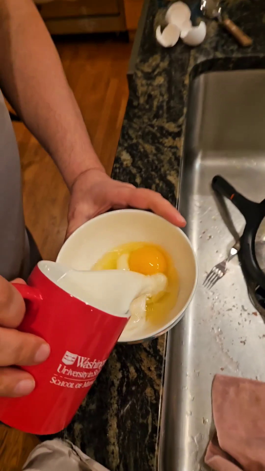 Adding milk to eggs in a bowl.