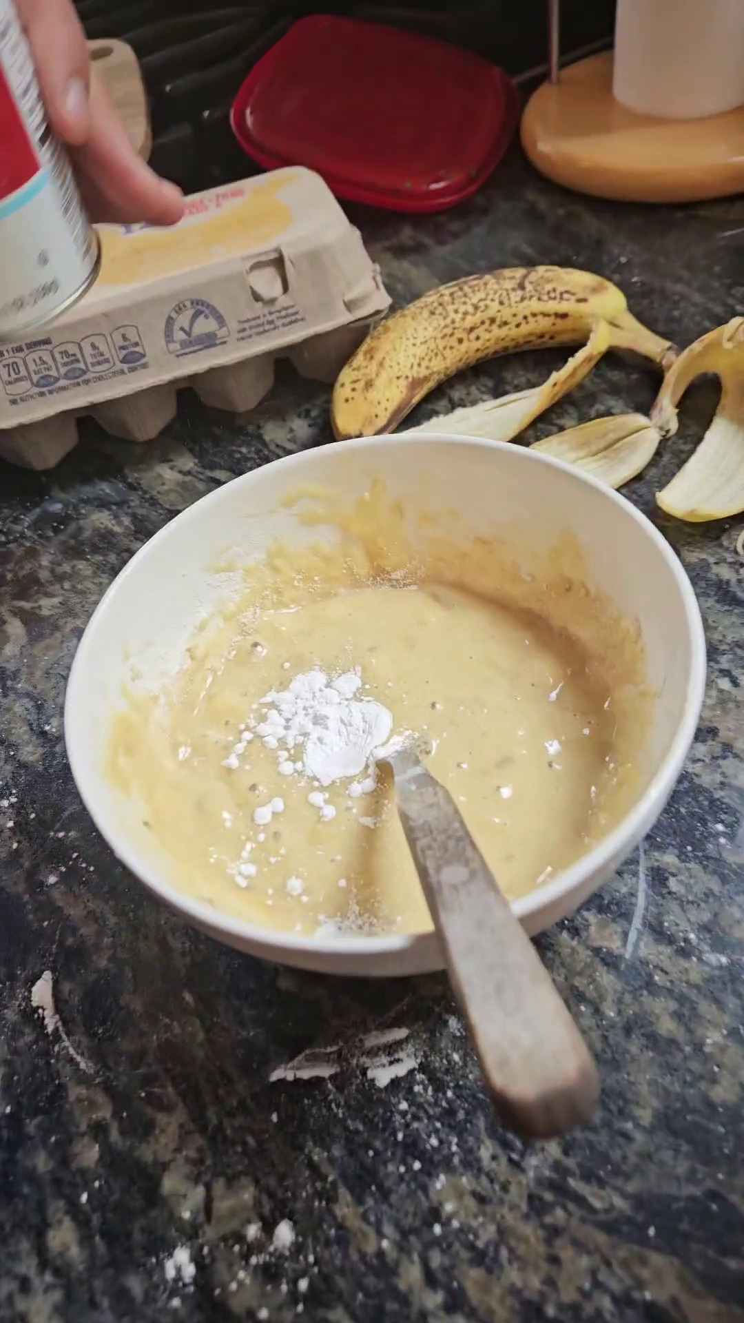 Adding baking powder to banana bread batter.