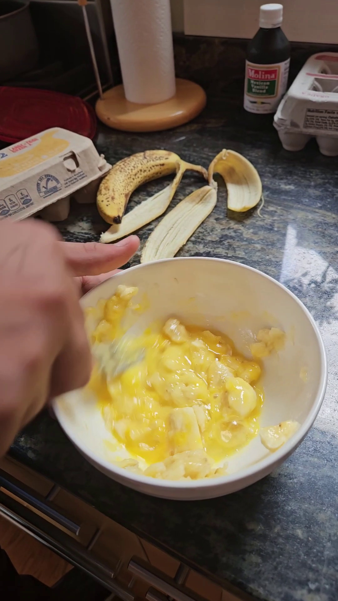 Combining egg with mashed banana in a mixing bowl.