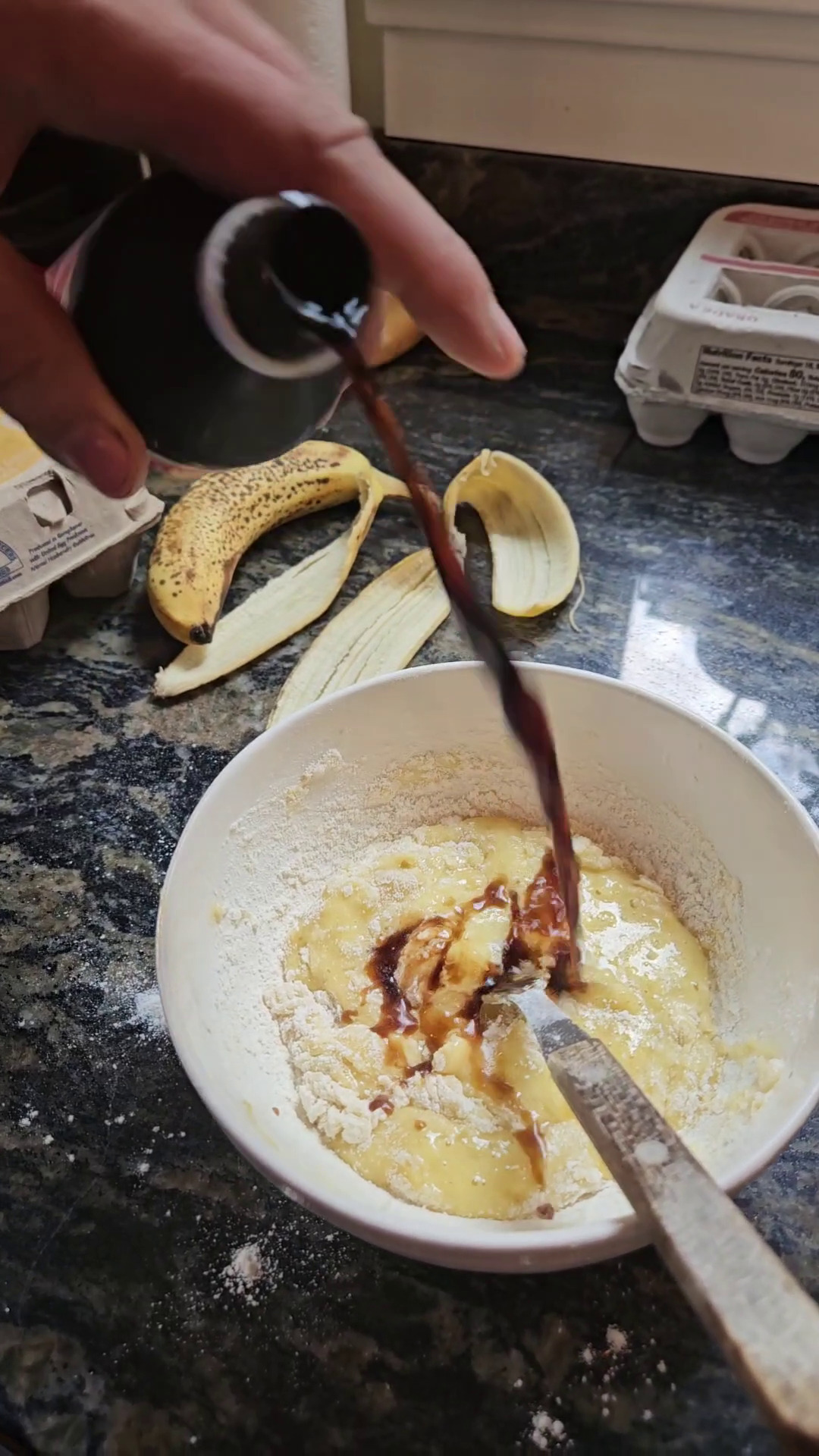 Pouring vanilla extract into microwave banana bread batter.